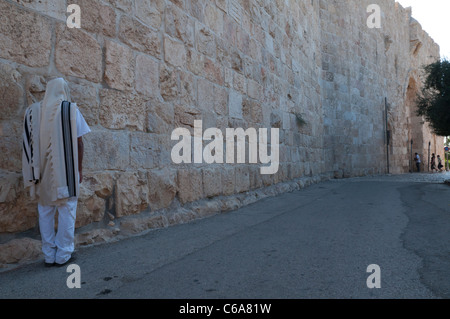 Jew with prayer shawl praying by City Walls near Zion Gate. Jerusalem Old City. Israel Stock Photo