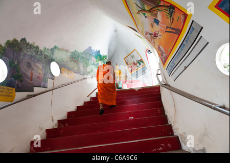 A Buddhist monk climbs the stairs inside the Dragon Temple Kanchanaburi Thailand Stock Photo