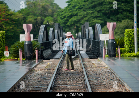 A woman crosses the River Kwai bridge and railway track, Kanachanaburi, Thailand Stock Photo