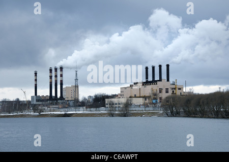 heavy smoke comes out from industrial plant pipes over river waters Stock Photo