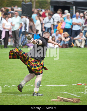 Kilted athlete in the 'throwing a 28lb' competition  weight during one of the 'heavy events' at Brodick Highland Games, Arran Stock Photo