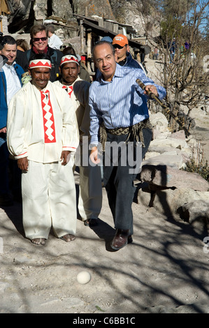 President Calderon tries out a game with a stick and a ball with native people at rim of Copper Canyon in Mexico Stock Photo