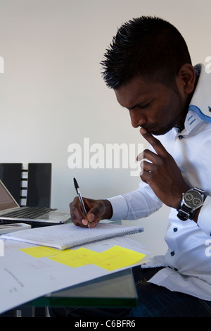 Young indian man studying on his desk Stock Photo