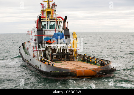 A tug boat tows the jack up barge the Goliath towards the Walney Offshore wind farm project Stock Photo