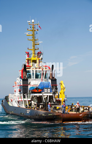 A tug boat towing a jack up barge, the Goliath, out to work on the Walney offshore wind farm off south Cumbria, UK. Stock Photo