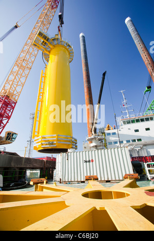 A crane lifts a transition piece onto the deck of a barge, ready to take out to the Walney offshore wind farm Stock Photo