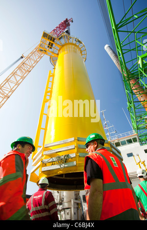 A crane lifts a transition piece onto the deck of a barge, ready to take out to the Walney offshore wind farm Stock Photo