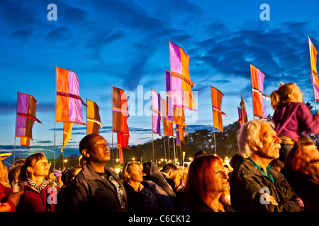 Festival goers at dusk at WOMAD 2011, Charlton Park, Malmesbury, Wiltshire, England, UK with iconic flags in background Stock Photo