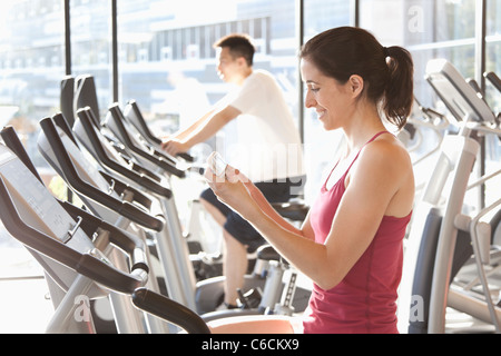 Woman on treadmill text messaging on cell phone Stock Photo