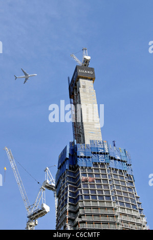 Work in progress on London Shard landmark skyscraper building under construction with four engined jet airliner flying overhead Southwark South London Stock Photo