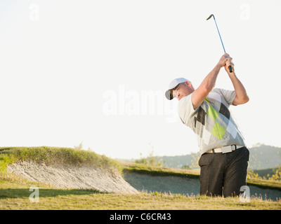 Caucasian golfer hitting ball out of bunker Stock Photo