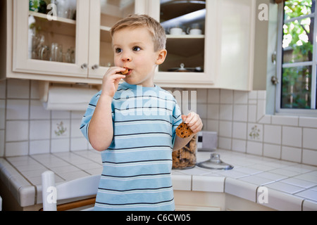 Caucasian boy eating cookie in kitchen Stock Photo