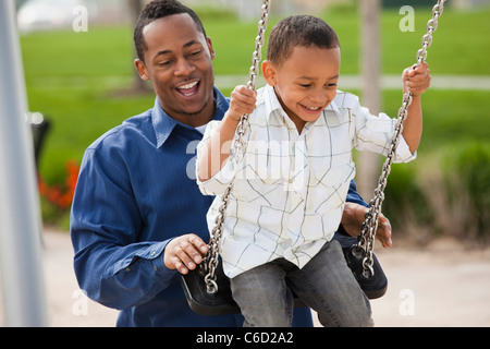Father pushing son on swing