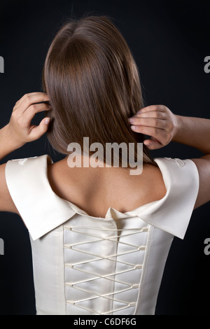 Beautiful slim girl in a wedding dress with a corset back in the studio on a black background Stock Photo