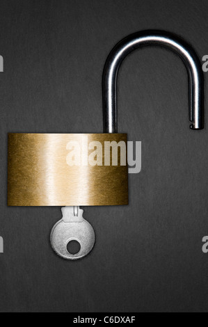 Open padlock and key on a dark slate background Stock Photo