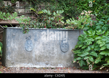 Old metal water trough,dated 1803 and bearing the crest of the Sitwell family in the gardens of Renishaw Hall, near Sheffield Stock Photo