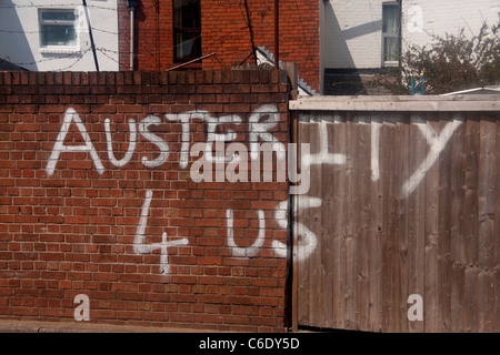 Graffiti condemning economic policy Money 4 War Bonuses 4 Banks Austerity 4 Us White paint on red brick wall Cardiff Wales UK Stock Photo