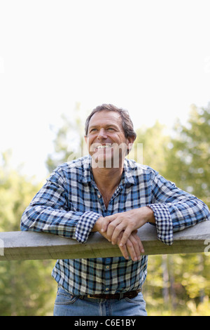 Caucasian man leaning on wooden fence Stock Photo