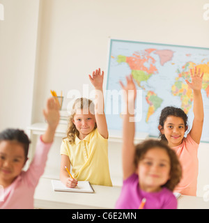 USA, New Jersey, Jersey City, four girls raising hands in classroom Stock Photo