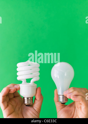 Hands comparing lightbulbs Stock Photo