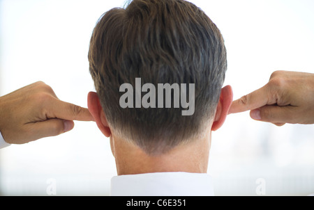 USA, New Jersey, Jersey City, Businessman plugging ears Stock Photo