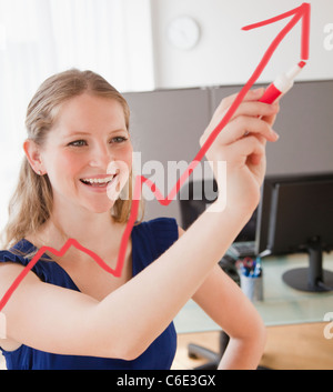 USA, New Jersey, Jersey City, Young woman drawing increasing line with arrow Stock Photo