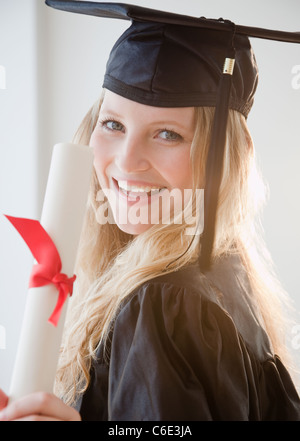 USA, New Jersey, Jersey City, Young woman wearing graduation gown with diploma Stock Photo