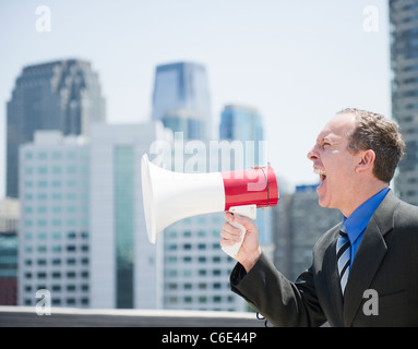 USA, New Jersey, Jersey City, Businessman shouting through megaphone Stock Photo