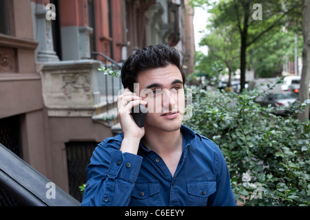 USA, New York, New York City, Young man talking on mobile phone on street Stock Photo