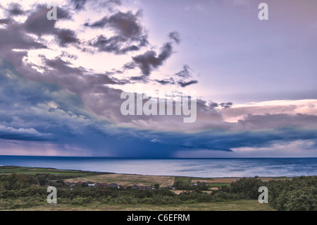 Looking our from Incleborough Hill, Norfolk, over West Runton to storm at sea, dusk. Stock Photo