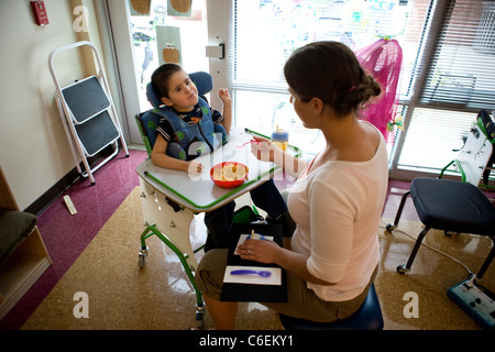 Speech therapist working with young boy on making a request for more food using sign language. Stock Photo