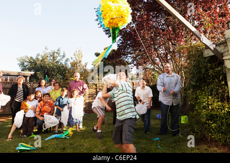 Hispanic family breaking pinata in backyard Stock Photo