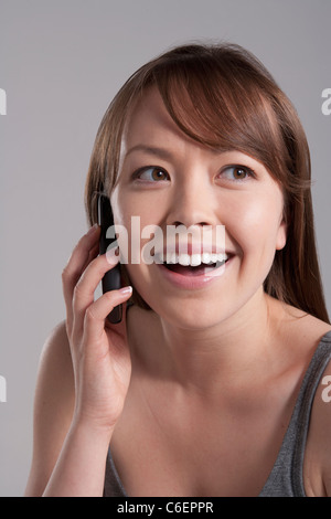 Portrait of young smiling woman using mobile phone, studio shot Stock Photo