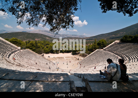 Two tourists take in the view at the Classical Greek theater at Ancient Epidaurus, Argolid, Peloponnese, Greece. Stock Photo