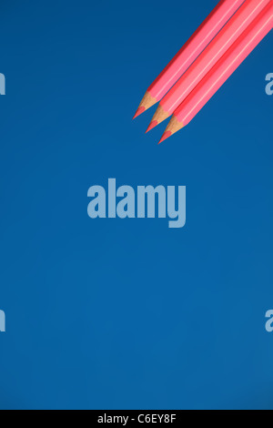 Three pink pencils on blue. Stock Photo