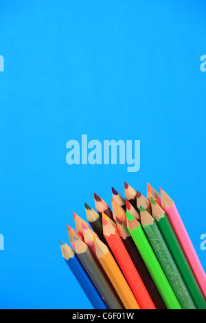 Multi coloured pencils in a pot, blue background. Stock Photo