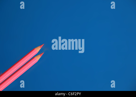 Two pink coloured pencils on a blue background. Stock Photo