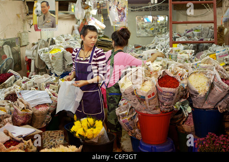 Two women working in a flower stall wrapping roses and Chrysanthemums in the Pak Klong Talat market (flower market) in Bangkok Stock Photo