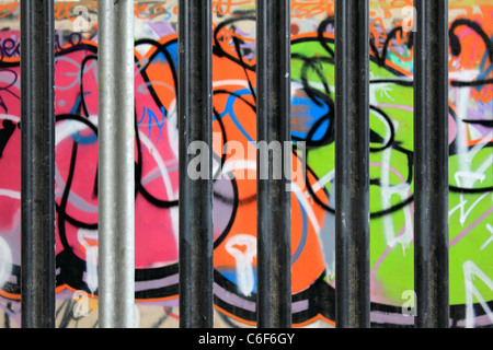 Graffiti behind bars on walls under the A316 flyover Hanworth, Surrey, England, UK Stock Photo