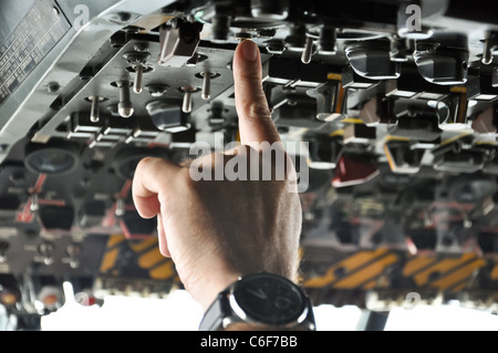 finger of a pilot pushing buttons in an airplane cockpit Stock Photo