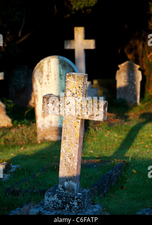 Cross headstones lit up in the early morning light. Kings Sutton, Nr Banbury, Northamptonshire, England Stock Photo