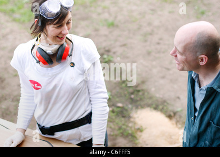 A Man and woman discuss over the sanding work of a wooden door, for the interior of a narrowboat. Stock Photo