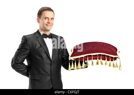 Man in a black suit with bow tie holding a pillow Stock Photo