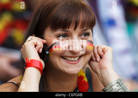 Germany supporter smiles while talking on her mobile phone at a 2011 Women's World Cup quarterfinal match between Germany/Japan. Stock Photo