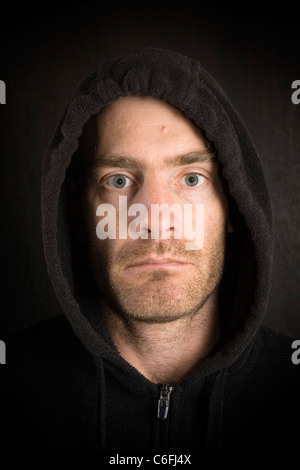 portrait of gritty scruffy hooded man in black Stock Photo