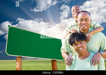 Attractive African American Family in Front of Blank Green Road Sign Ready for Your Own Message. Stock Photo