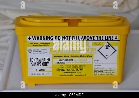 Clinical waste management uk close up yellow plastic box container for correct safe disposal of contaminated sharps seen on NHS hospital ward England Stock Photo