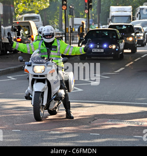 Metropolitan policeman officer on BMW motorbike in high vis jacket uniform on car motorcade met police escort duty stop pedestrian crossing London UK Stock Photo