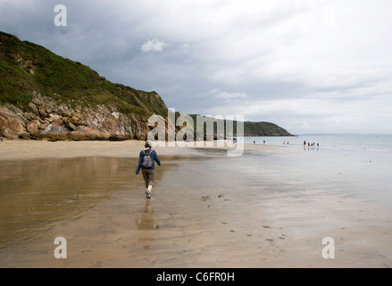 A lady walking on a sandy beach at Gorran Haven Cornwall Stock Photo