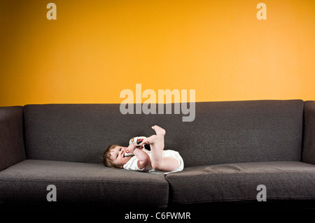 A baby girl lying on a sofa Stock Photo